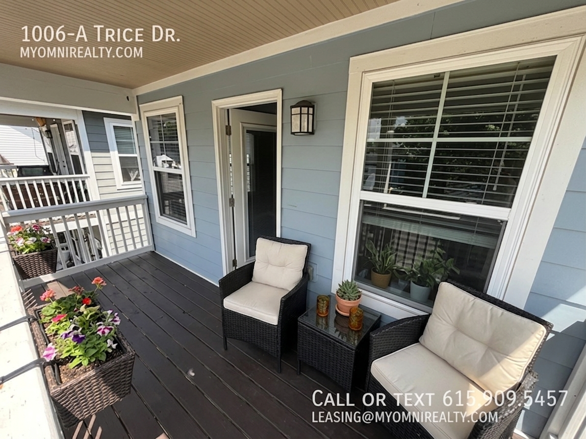 Porch seating area on a blue house with two cushioned wicker chairs, plants, and leasing info for 1006-A Trice Dr.