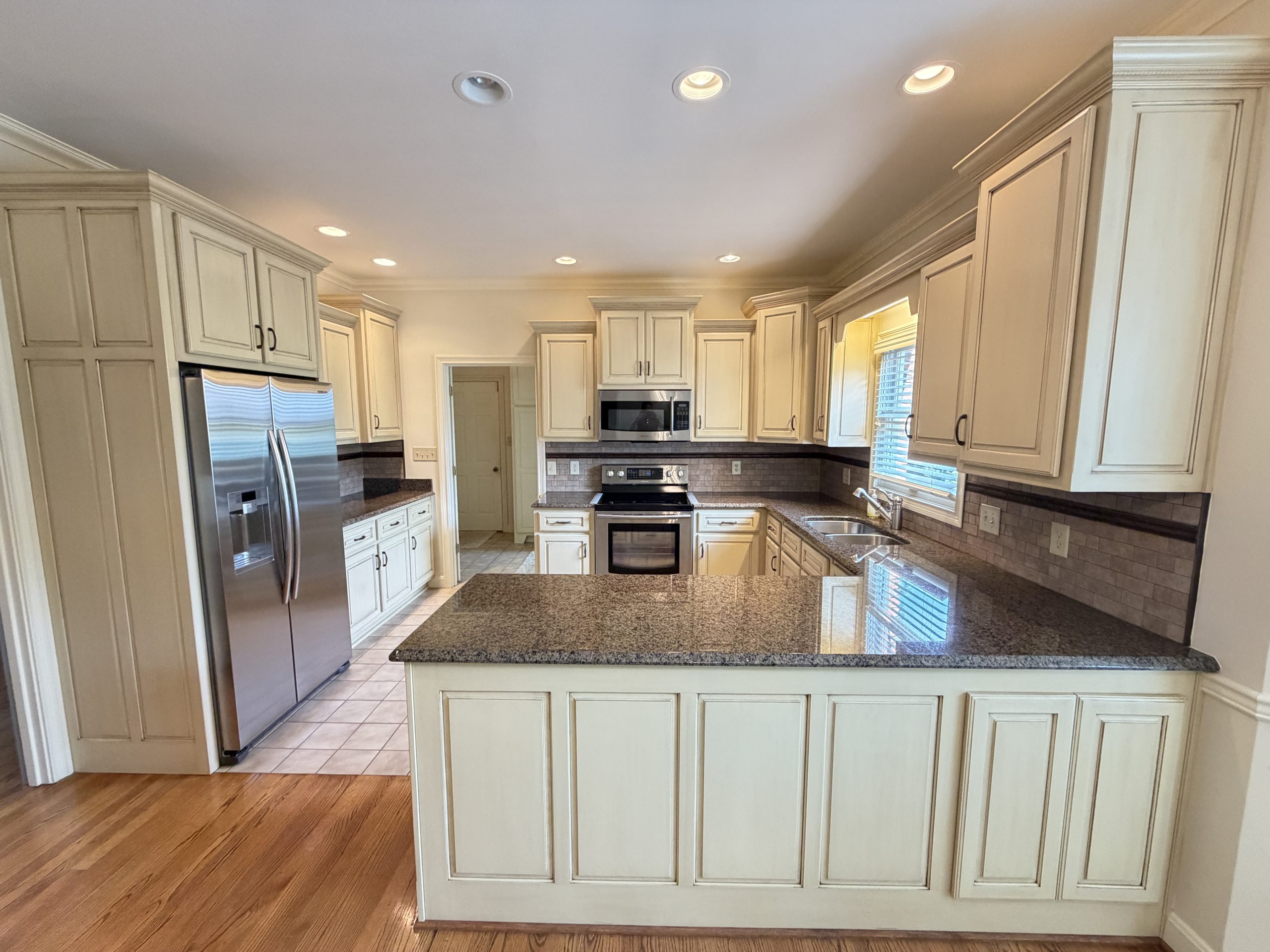 Kitchen with cream cabinets, granite countertops, stainless steel appliances, and an island in the center.