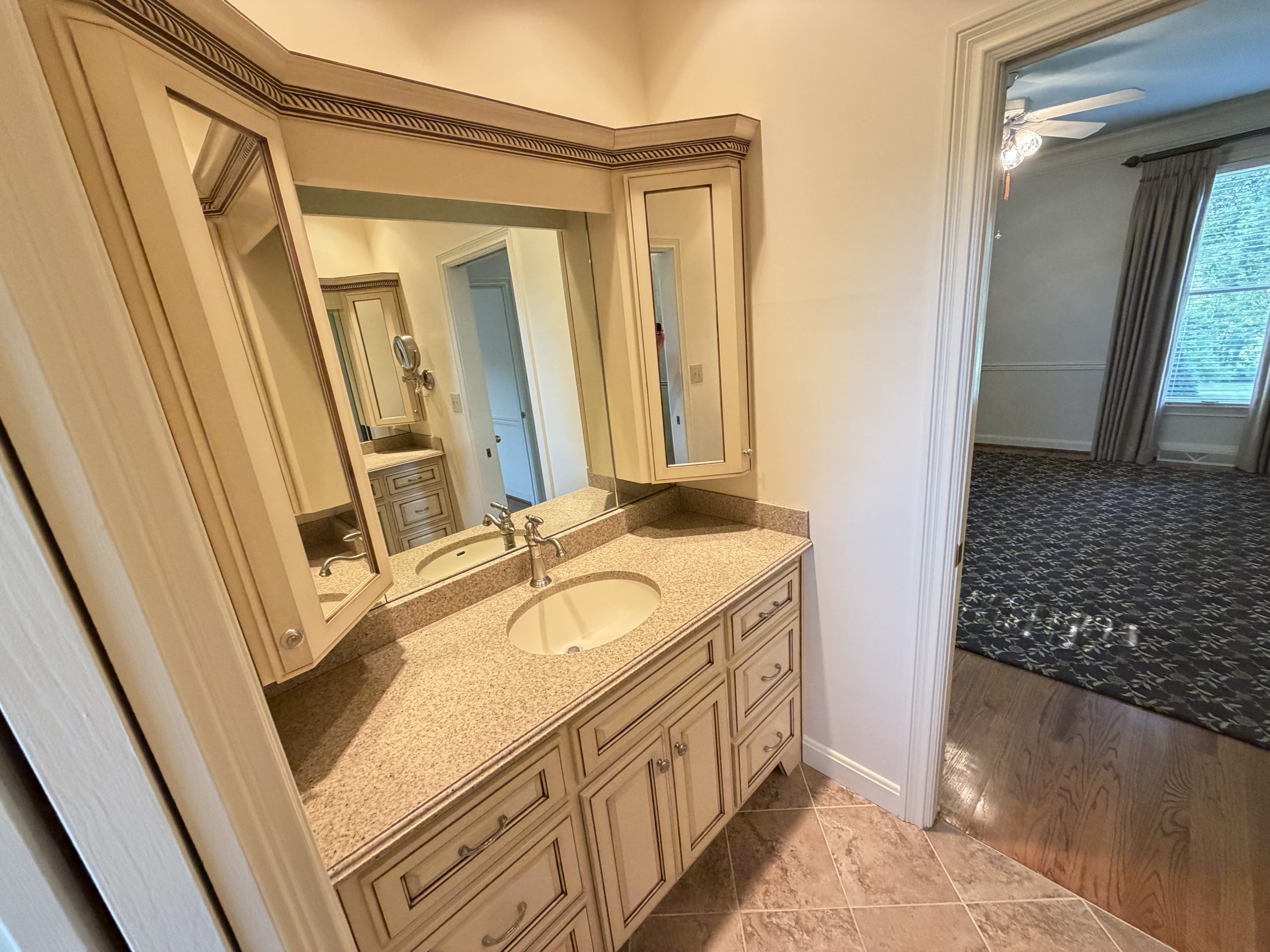 Double-sink bathroom vanity with beige cabinets, granite countertop, and framed mirrors